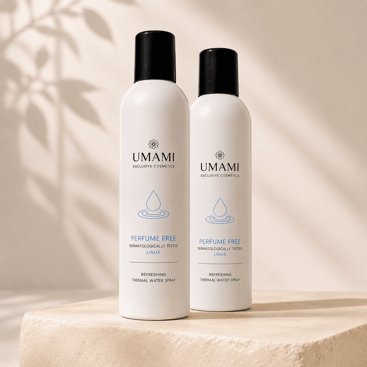 Twee witte spuitbussen UMAMI Exclusive Cosmetics Thermal Water Spray parfumvrij op een beige sokkel met bladschaduw